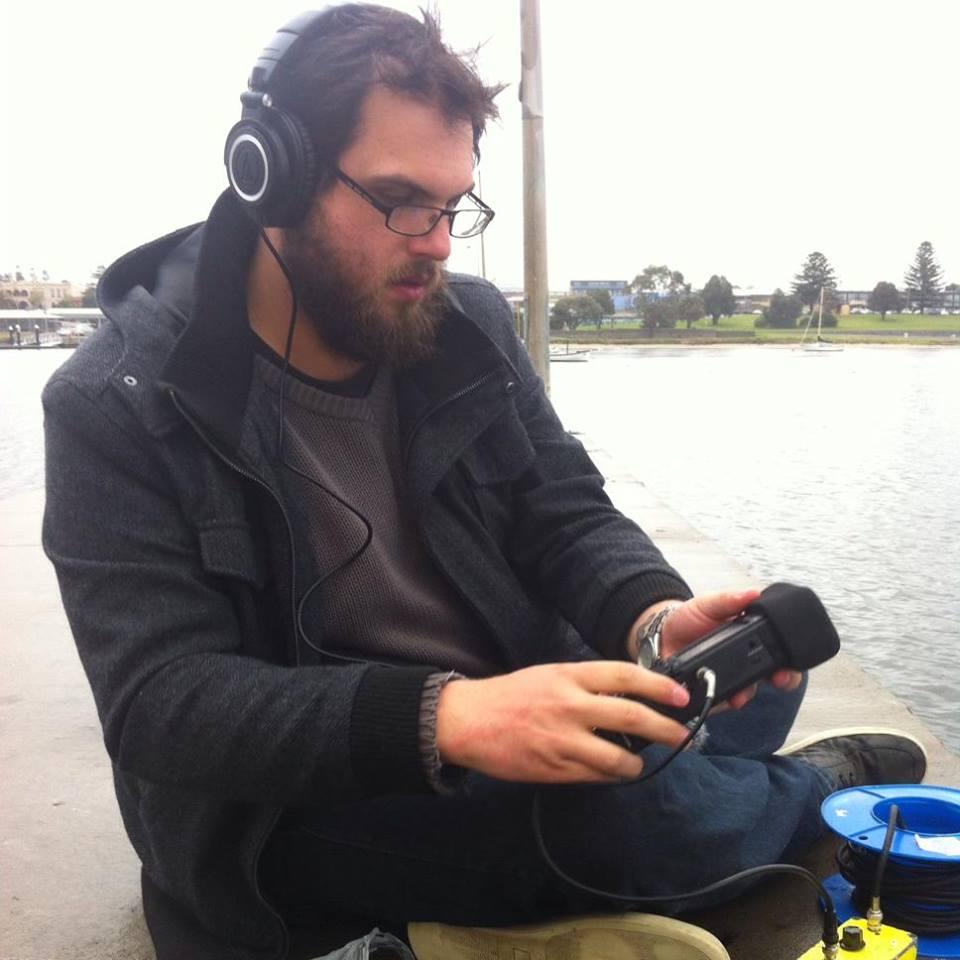 A photo of Vincent field recording near the ocean.